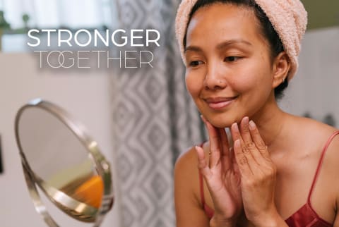 Woman washing her face in the mirror - Stronger Together