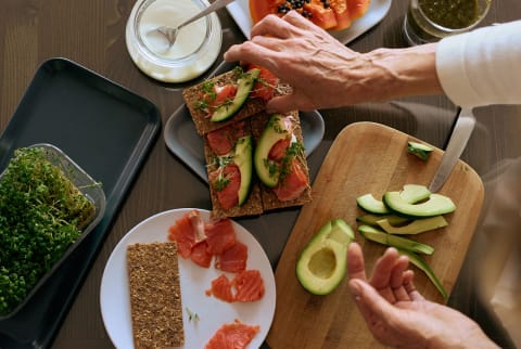 Woman preparing a meal with avocado and salmon