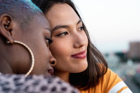 multiracial lesbian couple sitting close together outdoors