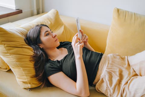 Young Woman Scrolling On Her Phone on the Couch