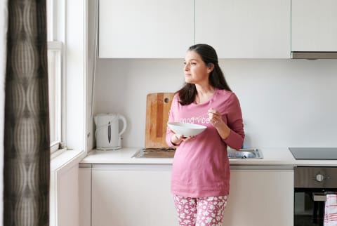 Smiling Woman Eating Breakfast In Her Kitchen