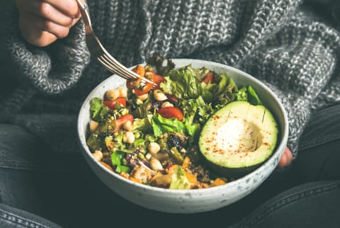 Woman eating fresh salad, avocado, beans and vegetables, square crop