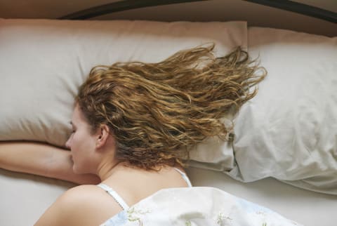 Woman Sleeping with wavy hair spread across pillow