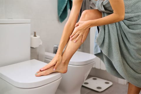 woman touching leg in bathroom