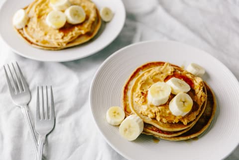 Two Plates Of Vegan Pancakes With Peanut And Banana
