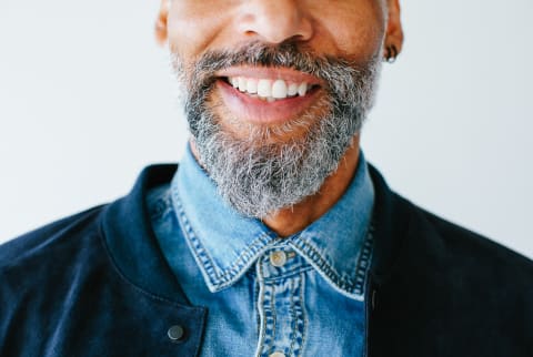 Closeup portrait of a cool man with a beard smiling on white