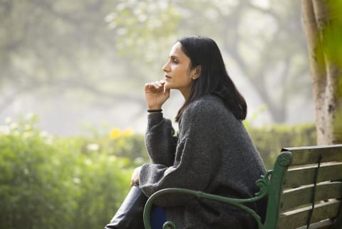 Woman lost in thought on a park bench