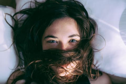 brunette women looking up at ceiling from pillow