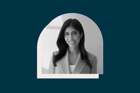 Black and white image of smiling woman in blazer on navy blue background