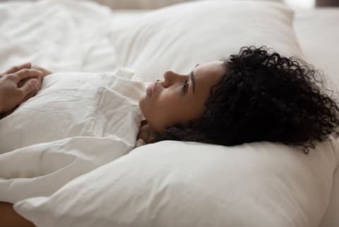 African American woman with open eyes lying in bed