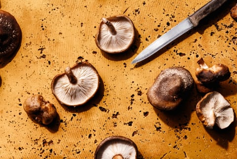 shiitake mushrooms on mustard yellow background with knife
