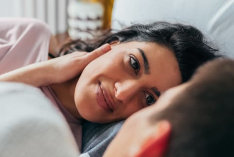 Couple laying in bed looking at each other