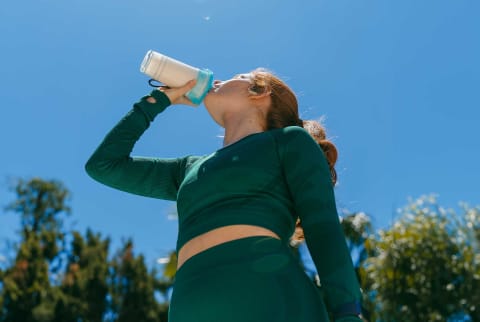 woman drinking protein shake outside