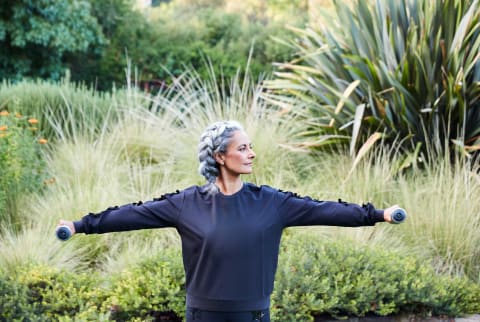 Older/mature woman working out with hand weights in nature