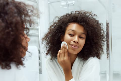 Woman Doing Skincare Routine in the Mirror