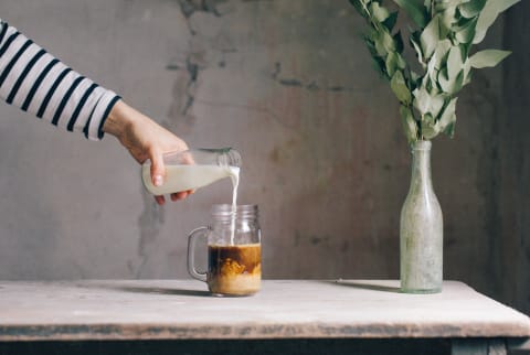 milk pouring into a glass of ice coffee