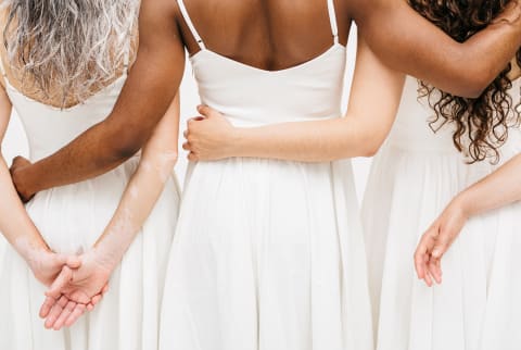 Mixed race women with hands on each other's backs