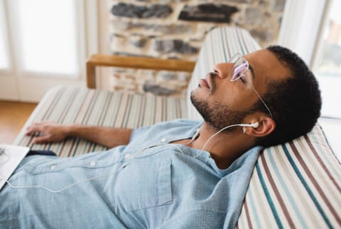 Man Relaxing on a Couch and Listening to Music