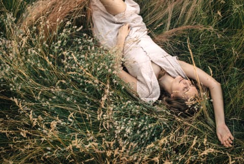 From above view horizontal portrait of dreamy model laying on grass with closed eyes