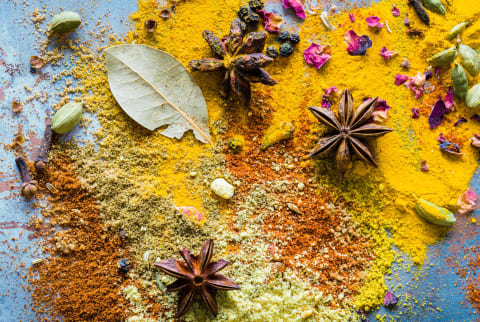 Overhead flat lay of various spices like star anise, bay leaves and turmeric