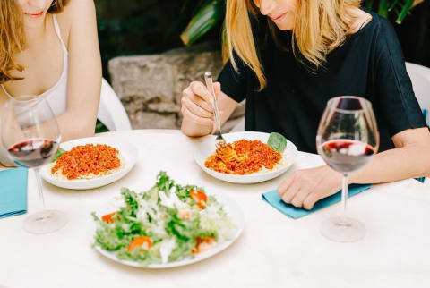 Women Sitting at Restaurant Eating Spaghetti and Drinking Wine