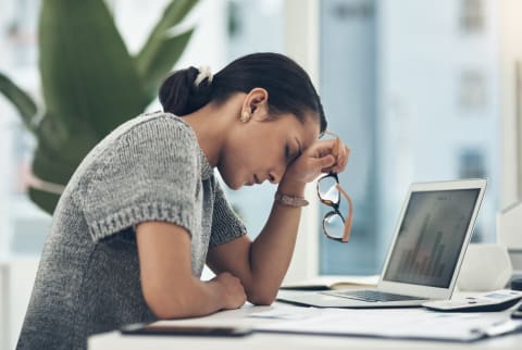 Busy stressed woman holding glasses in front of computer screen