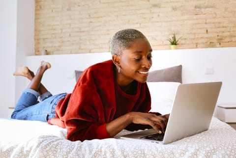 Woman Lying on Bed With a Laptop