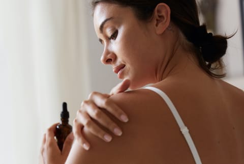 Young Woman Applying Body Serum To Smooth Her Skin
