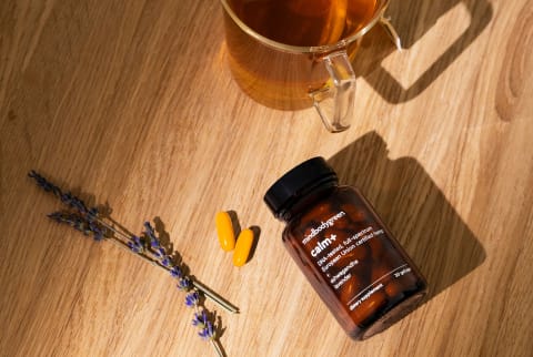 bottle of calm+ supplement on wood surface next to lavender sprigs