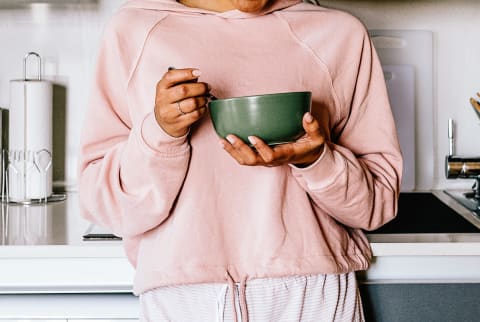 Unrecognizable Woman Eating a Bowl of Cereal In Her Kitchen