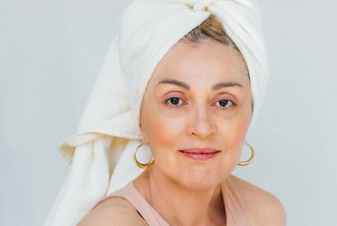Portrait of a beautiful woman in her 60s with a towel on her head, looking at camera