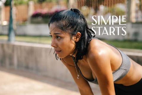 women outside exercising in sports bra with hands on knees taking a break