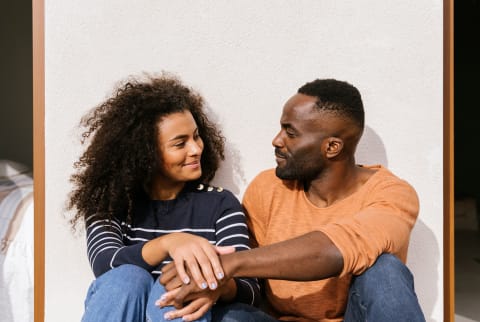 A man and woman smiling at each other, holding hands.