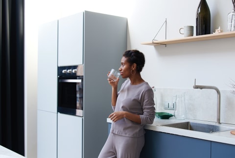 woman drinking water in kitchen