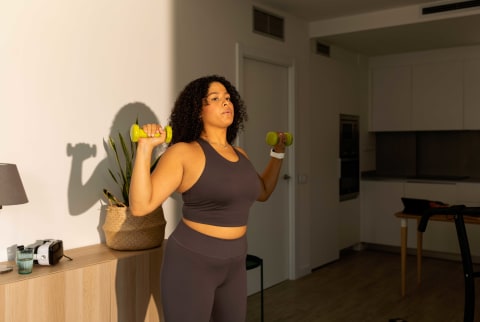 Woman using hand weights wearing a work out set in her living room