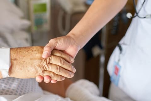 Health practitioner holding the hand of an elderly patient