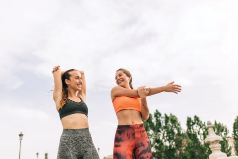 two women stretching outside in athleisure