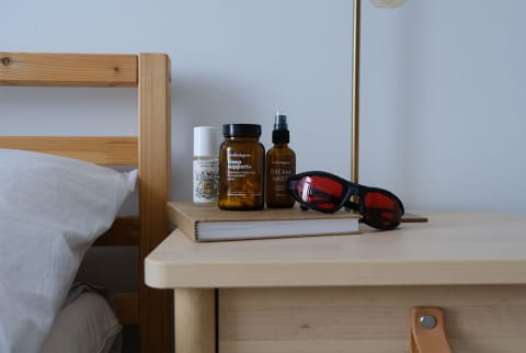 nightstand with red glasses, sleep supplement, pillow mist, journal