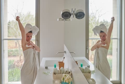 Woman Wrapped In Towel Applying Deodorant In Bathroom