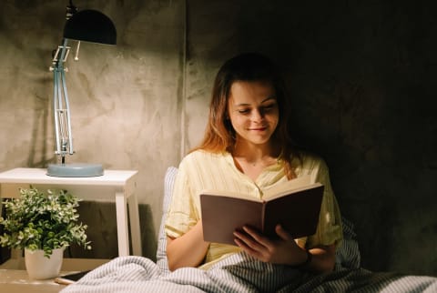 Young Woman Reading A Book In Bed