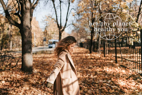 Woman dancing in autumn leaves - Healthy Planet Healthy You