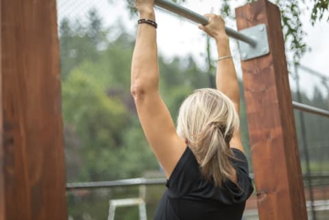 Woman doing a pull up out in an outdoor gym