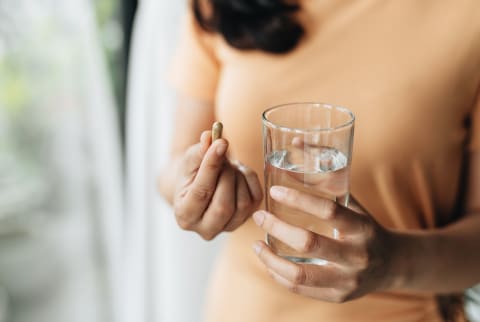 Woman taking a supplement with water