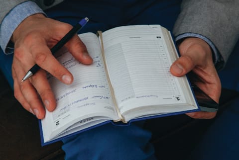 crop of mans hangs writing in journal