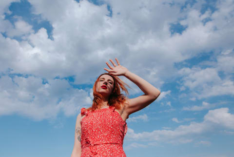 Young woman feeling groggy with a blue sky background