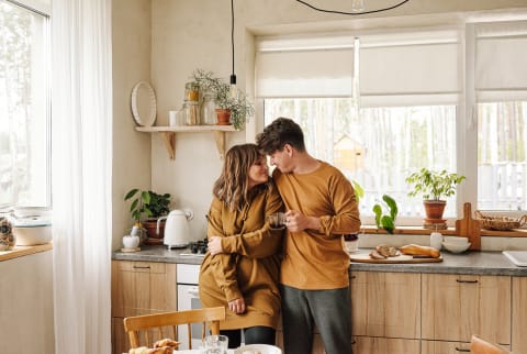 Married couple in love wearing casual outfit spending time together standing in modern kitchen