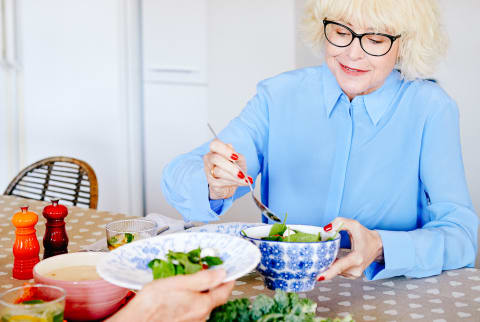 Older Woman Sitting at Table Eating Salad