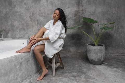 woman applying body oil before a shower