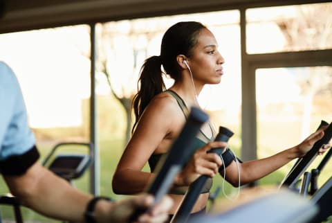 profile of a woman workout out on an elliptical machine