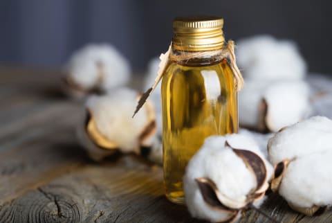 Cottonseed oil in a glass bottle on a wooden surface